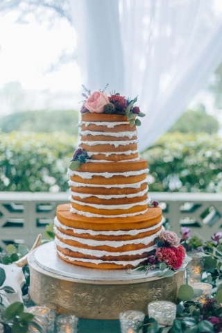 Naked wedding cake with fresh flowers in hot pink and raspberry.