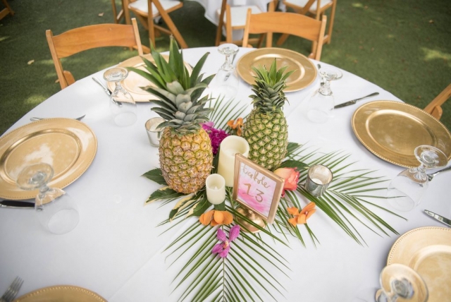 Simple tropical centerpiece featuring pineapples and orchids.