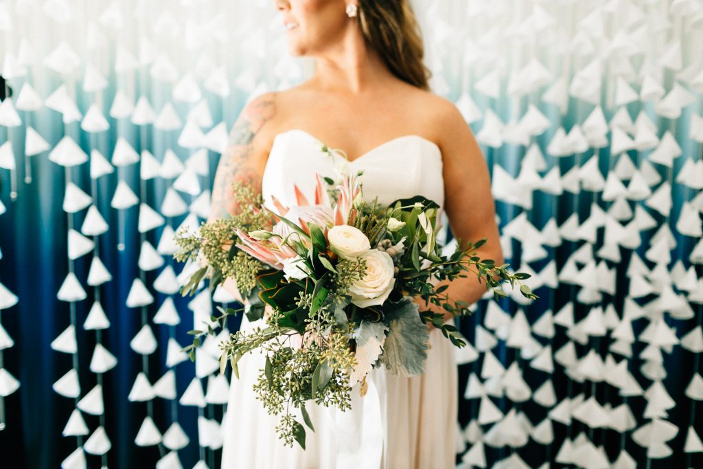 Bohemian bridal bouquet of king proteas, ranunculus, garden roses, dusty miller, eucalyptus and lisianthus.