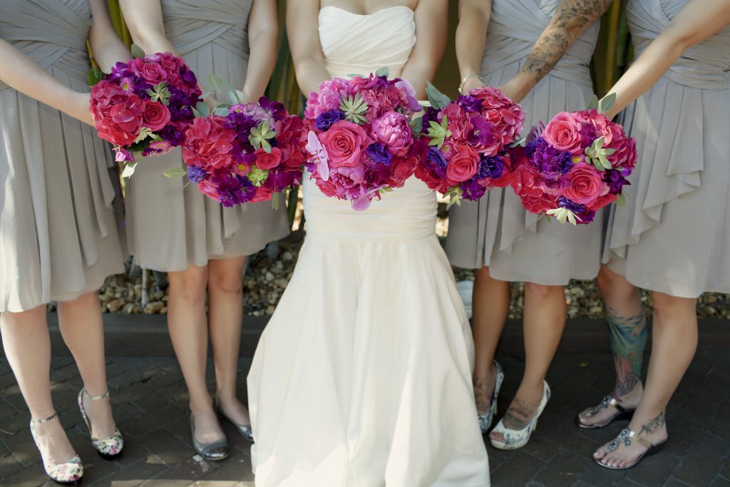 Bridal and bridesmaids bouquets in hot pinks and purple of hydrangeas, roses, peonies,  succulents, lisianthus and orchids.