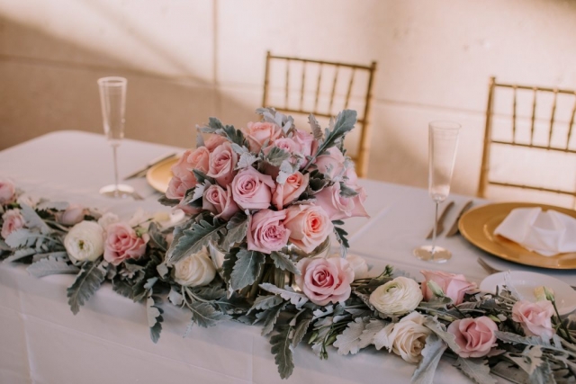 Soft winter sweetheart table with a garland and centerpiece with light pink roses and dusty miller.