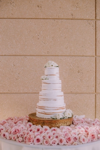 Wedding cake with fresh flowers surrounded by lush table of light pink roses.