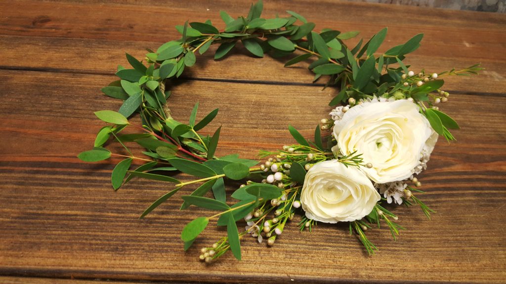 Asymmetrical flower crown of white ranunculus, wax flower and eucalyptus.