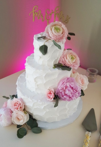 Wedding cake flowers with fresh pink and blush ranunculus, peonies and roses.