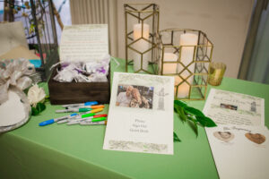 Guest book table decorated with lanterns and greenery for anniversary party.