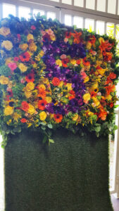 Colorful fresh flower wall photo backdrop for corporate anniversary event.