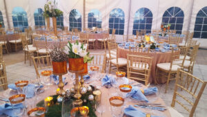 Mixture of low and elevated centerpieces of white, blue and gold for corporate holiday event.