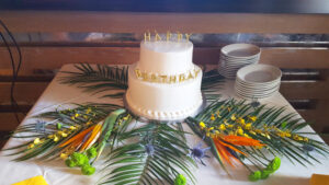 Tropical flowers and greenery decorating cake table for birthday party.