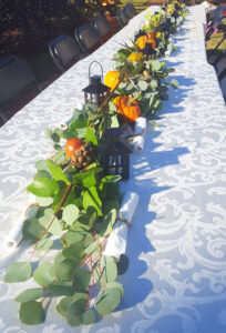 Greenery garland with pumpkins and lanterns down Thanksgiving table.