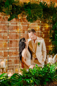 Sweetheart head table backdrop of tropical greenery, lights and candles at wedding reception at Nova 535 in St. Petersburg, Florida.