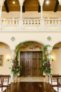 Organic and colorful arch of raspberry colored flowers for wedding ceremony at Avila Country Club in Tampa, Florida.
