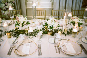 Classic and romantic all white feasting table with floating and taper candles at wedding reception at Vinoy Grand Ballroom in St. Petersburg, Florida.