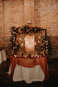 Boho fall inspired sweetheart table backdrop with pampas grass and light bulbs at Armature Works in Tampa, Florida.