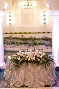 Romantic garden style arrangement on sweetheart table and garland at wedding reception at the Vinoy in St. Petersburg, Florida.
