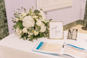 White flower arrangement on sign in table for wedding reception at Museum of Fine Arts in St. Petersburg, Florida.