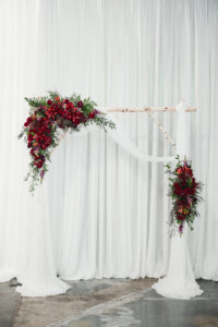 Moody red flower and birch arch for wedding ceremony at Flying Boat Brewing in St. Petersburg, Florida.