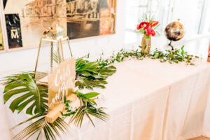 Tropical modern welcome table with greenery at wedding reception at Tampa River Center in Tampa, Florida.