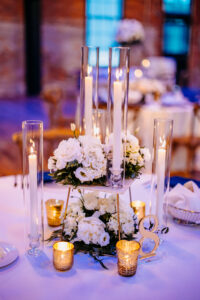 Tiered white flower centerpiece with taper candles at wedding reception at Armature Works in Tampa, Florida.