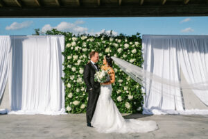 Classic white flower and greenery wall for outdoor wedding ceremony at Tampa River Center in Tampa, Florida.