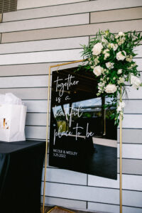 White flower and greenery corner piece on welcome sign to wedding reception at Tampa River Center in Tampa, Florida.