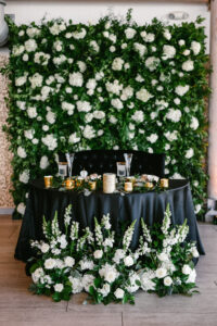 Greenery and white flower sweetheart table backdrop and arrangements at wedding reception at Tampa River Center in Tampa, Florida.