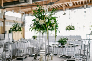 White flower and greenery elevated centerpiece at wedding reception at Tampa River Center in Tampa, Florida.