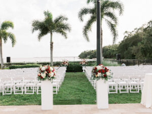 Red and white aisle entrance arrangements at outdoor wedding ceremony in Tampa, Florida.