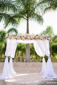 White and pink flower header on an arbor for an outdoor wedding ceremony in St. Petersburg, Florida.