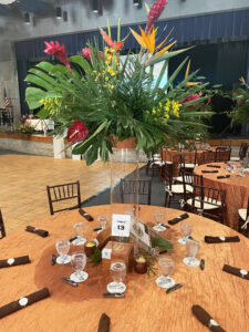 Tropical elevated centerpiece and cigar boxes on guest table for Havana Nights themed school fundraising gala.