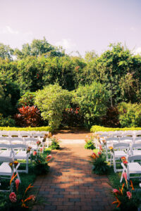 Colorful tropical aisle arrangements at garden wedding ceremony at Sunken Gardens in St. Petersburg, Florida.