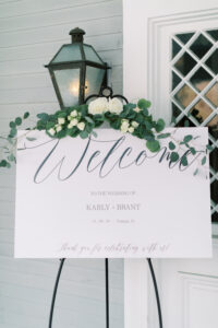 Simple white flower and greenery piece on welcome sign for wedding reception at the Orlo House in Tampa, Florida.