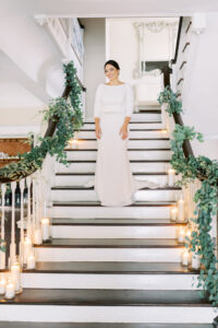 Greenery garland and candles cascading down staircase at wedding at the Orlo House in Tampa, Florida.