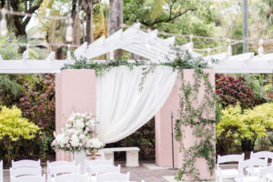 Asymmetrical organic and garden style alter with greenery and white flowers for outdoor wedding ceremony in the Vinoy Tea Garden in St. Petersburg, Florida.