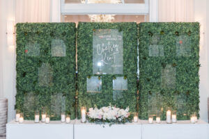 Candles and white flower arrangement in front of seating chart wall for wedding reception in Vinoy Grand Ballroom in St. Petersburg, Florida.