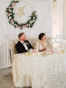 Romantic white and pink flower hoop and drapery backdrop behind sweetheart table with candles at wedding reception at Vinoy Grand Ballroom in St. Petersburg, Florida.