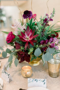 Moody low centerpieces of reds and purples at a wedding reception at the Museum of Fine Arts in St. Petersburg, Florida.