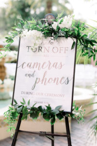 Greenery and white flowers on ceremony sign at wedding at the Vinoy Tea Garden in St. Petersburg, Florida.
