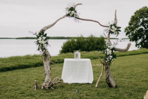 Organic all white flowers on driftwood arch for an outdoor wedding ceremony at Tampa Bay Watch in Tierra Verde, Florida.