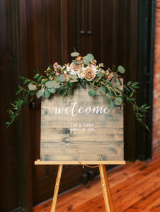 Garden style flower piece on welcome sign at wedding reception at Armature Works in Tampa, Florida.