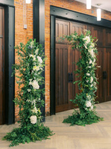 Organic and asymetrical open deconstructed arch of greenery and white flowers for wedding ceremony at Armature Works in Tampa, Florida.