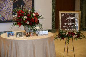 Red flower arrangement on welcome table and sign at wedding ceremony at Museum of Fine Arts in St. Petersburg, Florida.