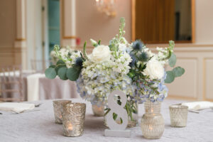 Classic and romantic white and blue low centerpiece with silver votives at wedding reception at Museum of Fine Arts in St. Petersburg, Florida.