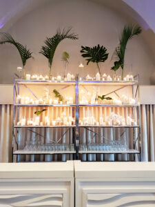 Dramatic candles and tropical greenery bar backdrop at wedding reception at the Vinoy Sunset Ballroom in St. Petersburg, Florida.