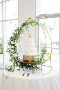 White flower and greenery garland on moon gate over cake at wedding reception in Tampa, Florida.