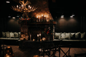 Rustic fireplace altar with organic flower arrangements and lanterns for wedding ceremony at Urban Stillhouse in St. Petersburg, Florida.