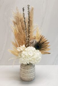 A boho arrangement with white hydrangea and mixed dried elements in a keepsake ceramic container