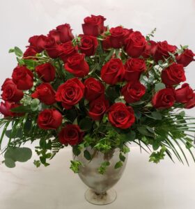 Six dozen red roses arranged in a grand container with bupleurum and eucalyptus.